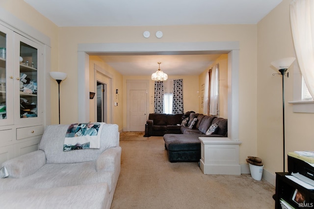 carpeted living room featuring an inviting chandelier