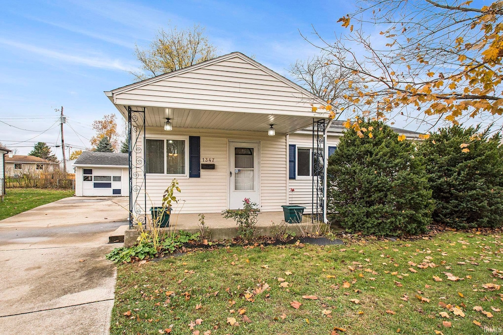 bungalow with a front yard, a porch, and an outbuilding