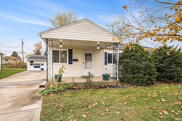 bungalow with a front yard, a porch, and an outbuilding