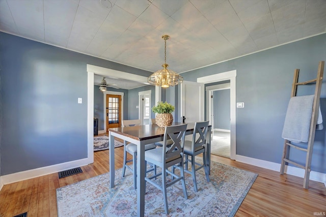 dining area featuring hardwood / wood-style flooring and ceiling fan with notable chandelier