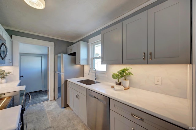 kitchen with appliances with stainless steel finishes, backsplash, gray cabinetry, crown molding, and sink