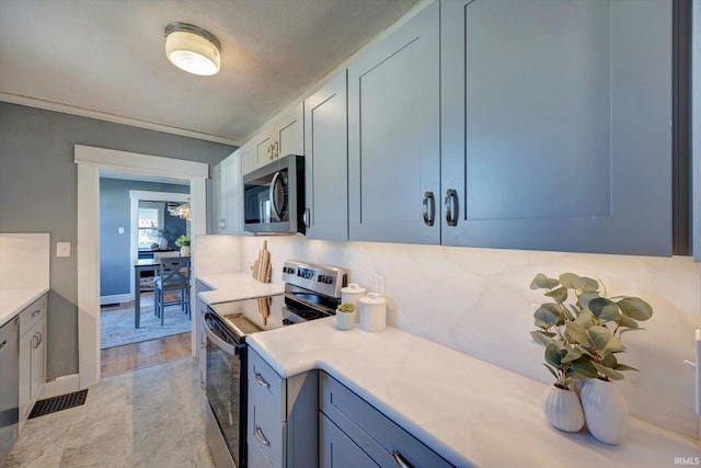 kitchen featuring light stone countertops, stainless steel appliances, crown molding, a textured ceiling, and light wood-type flooring