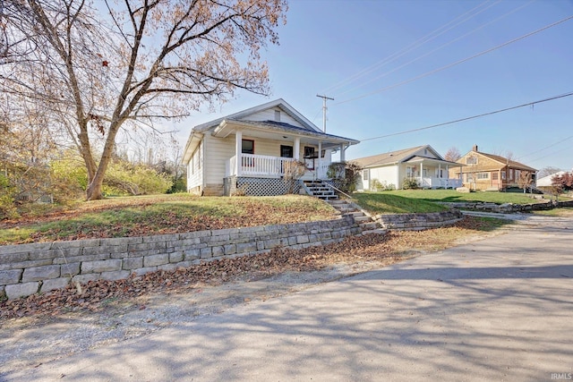 bungalow-style home featuring covered porch and a front yard