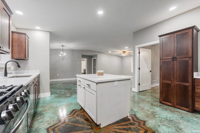 kitchen featuring white cabinets, sink, stainless steel stove, decorative light fixtures, and a kitchen island