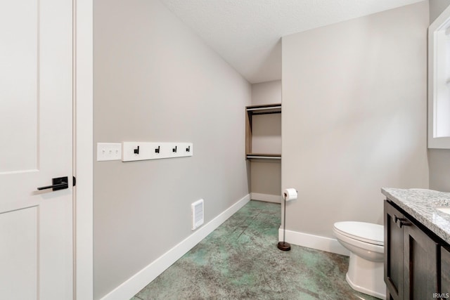 bathroom with vanity, toilet, and a textured ceiling