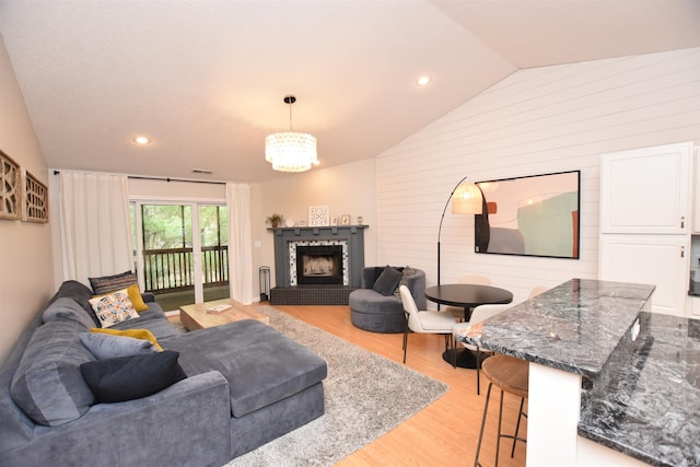 living room featuring a notable chandelier, light wood-type flooring, and lofted ceiling