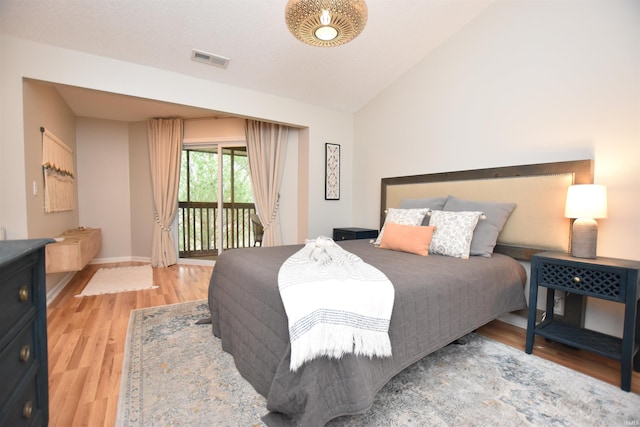 bedroom featuring access to exterior, wood-type flooring, and lofted ceiling