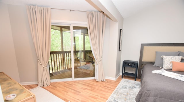 bedroom featuring access to exterior, wood-type flooring, and vaulted ceiling