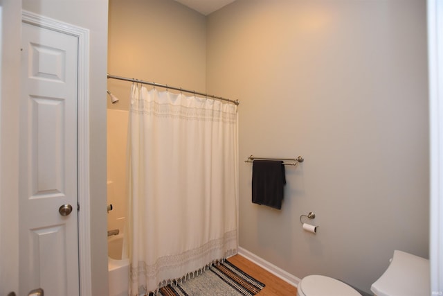 bathroom with wood-type flooring, shower / tub combo, and toilet