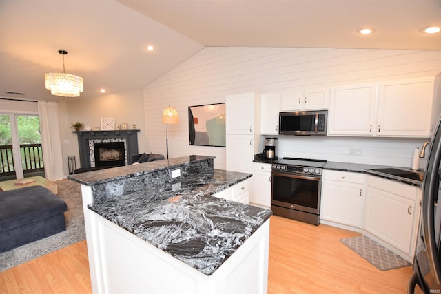 kitchen with hanging light fixtures, vaulted ceiling, appliances with stainless steel finishes, light hardwood / wood-style floors, and white cabinetry