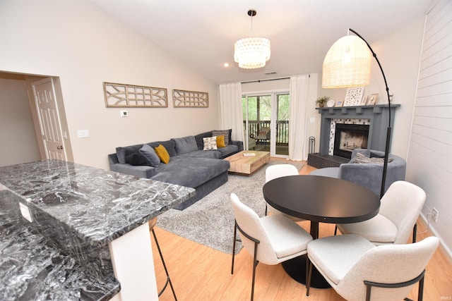 living room featuring light hardwood / wood-style flooring, vaulted ceiling, and an inviting chandelier