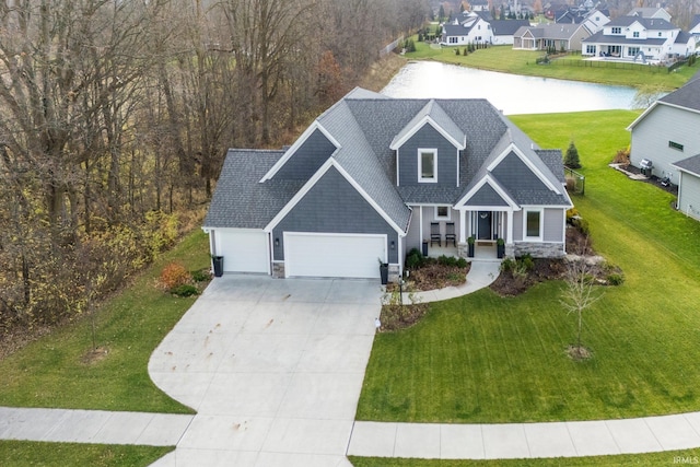 view of front facade featuring a front lawn, a water view, a porch, and a garage