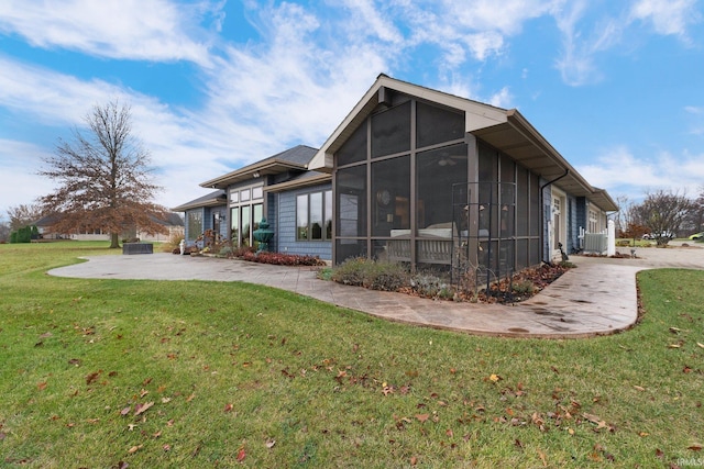 back of house featuring a sunroom, a patio area, and a lawn