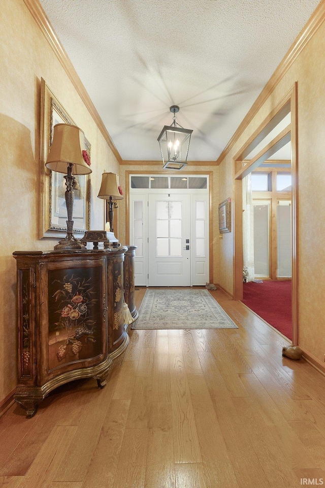 foyer with ornamental molding, a textured ceiling, and hardwood / wood-style flooring