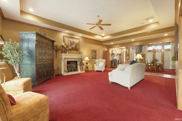 living room with carpet, a raised ceiling, and ceiling fan