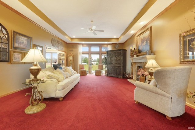 living room with a tray ceiling, ceiling fan, and carpet