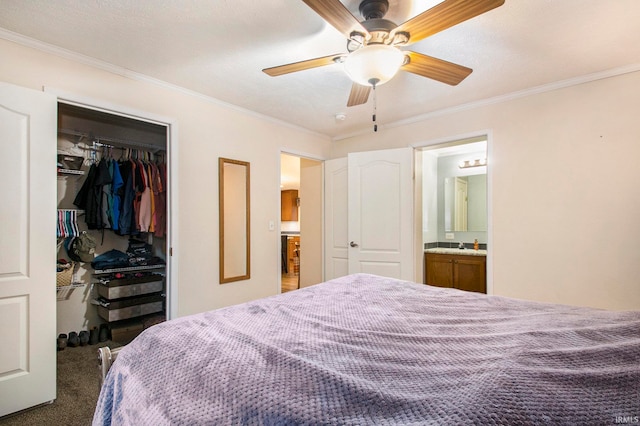 bedroom featuring dark carpet, ornamental molding, ceiling fan, connected bathroom, and a closet