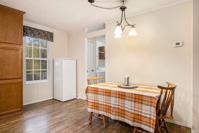 dining area featuring dark hardwood / wood-style flooring, crown molding, washer / clothes dryer, and a chandelier