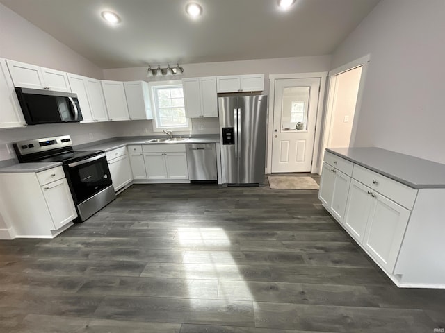 kitchen with sink, dark hardwood / wood-style floors, lofted ceiling, white cabinets, and appliances with stainless steel finishes