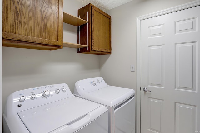 laundry area with cabinets, independent washer and dryer, and a textured ceiling