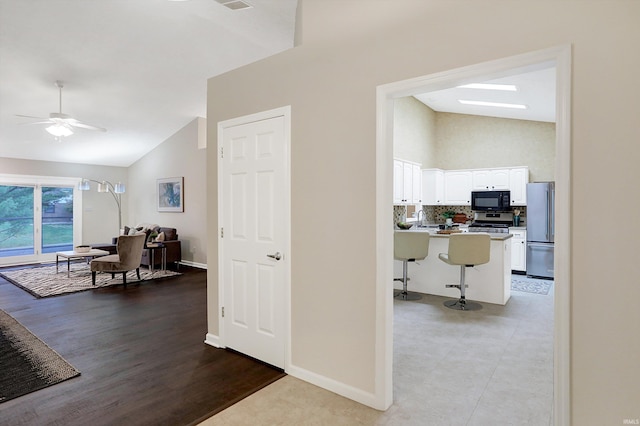 hall with light hardwood / wood-style flooring, vaulted ceiling, and sink