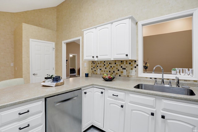 kitchen with white cabinetry, sink, tasteful backsplash, stainless steel dishwasher, and kitchen peninsula