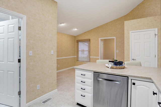 kitchen with stainless steel dishwasher, white cabinetry, light tile patterned floors, and vaulted ceiling