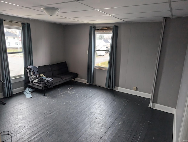 unfurnished room with a paneled ceiling, dark hardwood / wood-style floors, and a healthy amount of sunlight