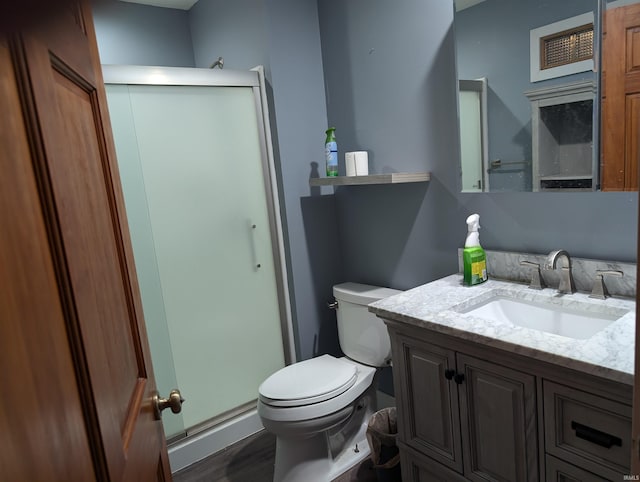 bathroom with wood-type flooring, vanity, toilet, and a shower with door