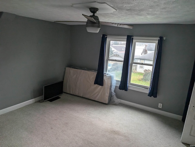 unfurnished room featuring ceiling fan, light colored carpet, and a textured ceiling