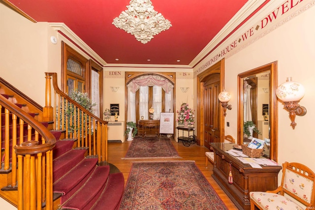 entrance foyer featuring dark hardwood / wood-style floors, crown molding, and a notable chandelier