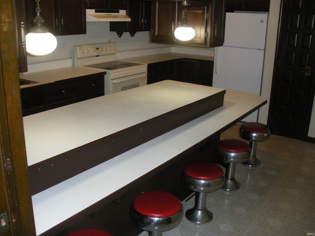 kitchen featuring a breakfast bar area, pendant lighting, and white appliances