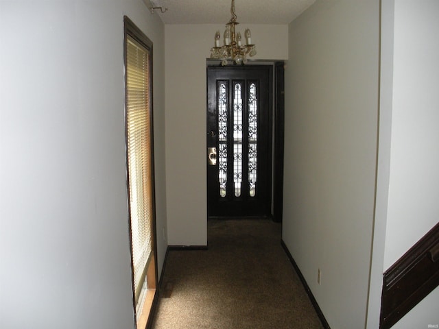 hallway featuring dark colored carpet and an inviting chandelier