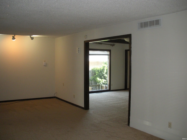 empty room featuring a textured ceiling and light colored carpet