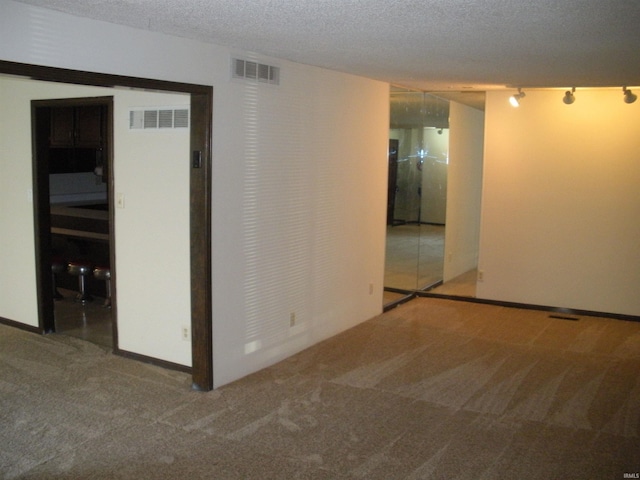 carpeted empty room featuring a textured ceiling