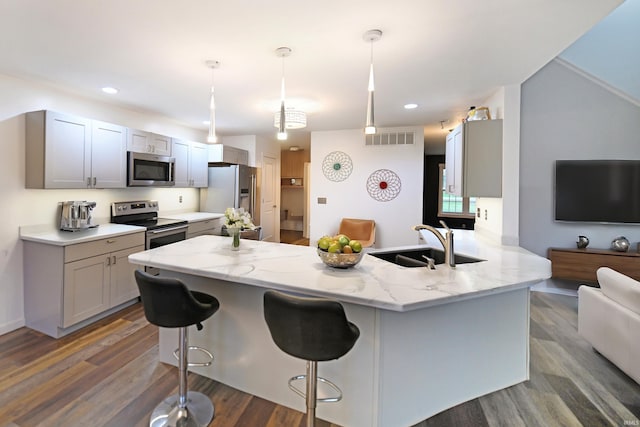 kitchen with stainless steel appliances, hanging light fixtures, dark wood-type flooring, and sink