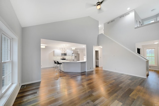 living room with dark hardwood / wood-style flooring, high vaulted ceiling, and ceiling fan