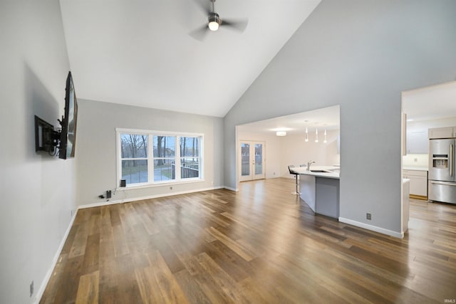 unfurnished living room with ceiling fan, dark hardwood / wood-style flooring, high vaulted ceiling, and french doors