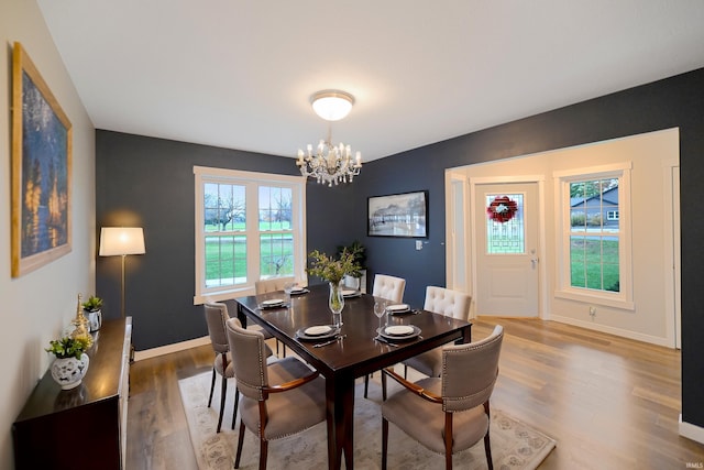 dining space featuring wood-type flooring and an inviting chandelier