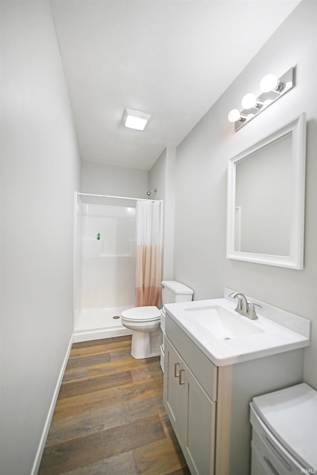 bathroom with hardwood / wood-style floors, vanity, toilet, and walk in shower