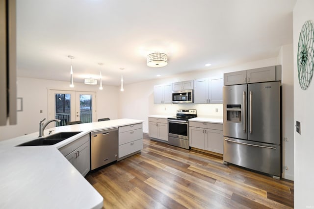 kitchen with appliances with stainless steel finishes, dark hardwood / wood-style flooring, sink, decorative light fixtures, and gray cabinets