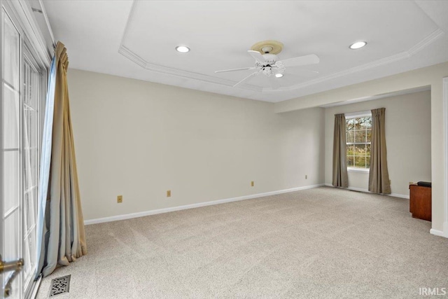 carpeted empty room featuring a raised ceiling, ceiling fan, and ornamental molding