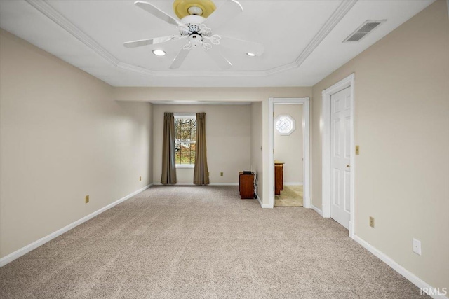 carpeted spare room with a tray ceiling, crown molding, and ceiling fan