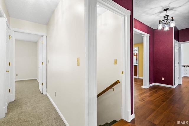 hall with dark hardwood / wood-style flooring, ornate columns, and a textured ceiling