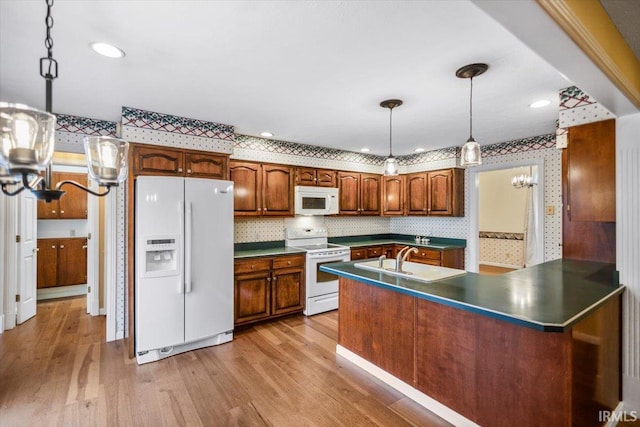 kitchen with pendant lighting, white appliances, light wood-type flooring, tasteful backsplash, and kitchen peninsula