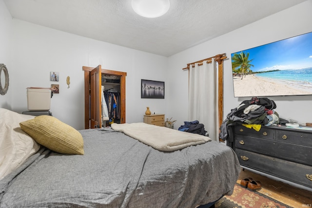 bedroom with a walk in closet, a textured ceiling, and a closet