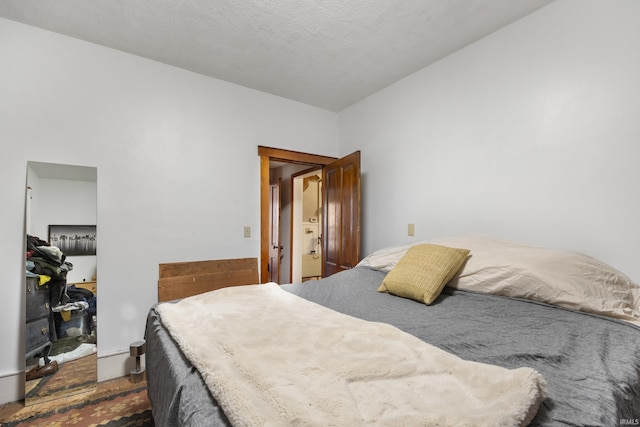 bedroom with lofted ceiling, a textured ceiling, and dark wood-type flooring