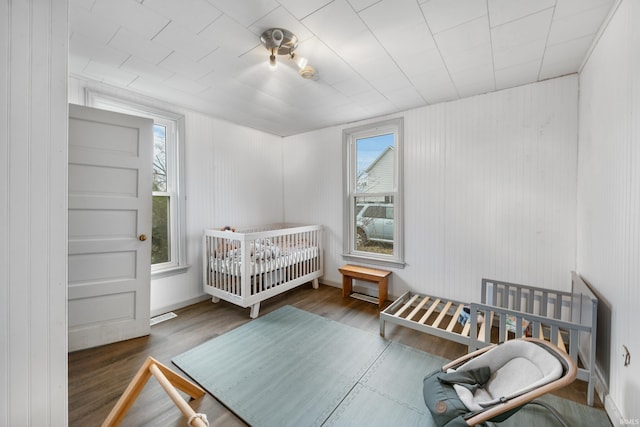 bedroom with dark hardwood / wood-style flooring and a nursery area