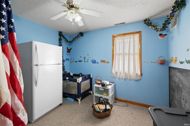 interior space featuring a textured ceiling, white fridge, and ceiling fan