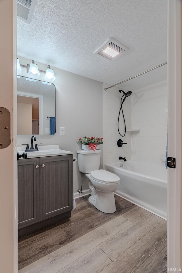 full bathroom featuring wood-type flooring, a textured ceiling, toilet, shower / washtub combination, and vanity